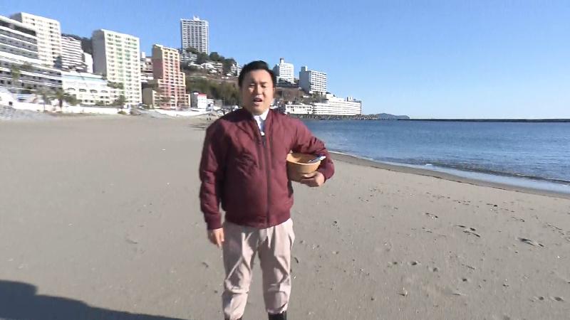風呂桶と温度計を準備したにむらあつとリポーターが海岸に立つ