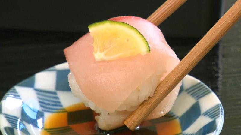 ブリのすしをしょうゆに付けて