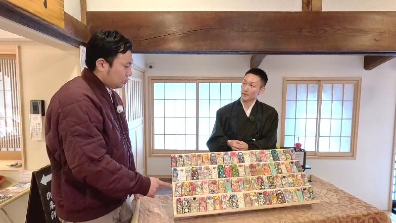 お守りを挟んで会話する副住職とにむらリポーター