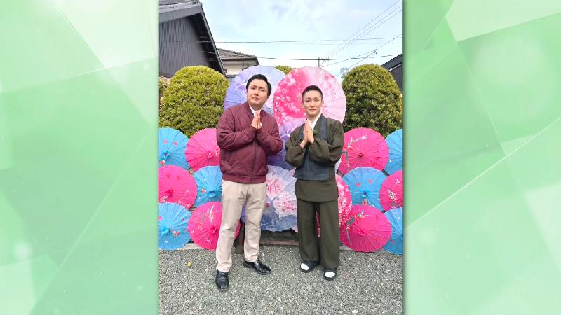 傘の装飾の前で写真を撮る副住職とにむらリポーター