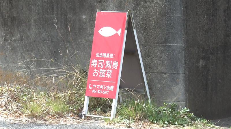 トンネルのかたわらに置かれたヤマボシ水産の看板