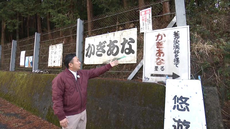 「かぎあな」の看板を指さすにむらリポーター