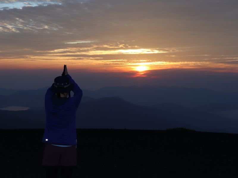 朝日に手を合わせる新間