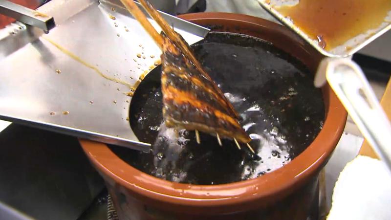 ウナギをタレにつけている