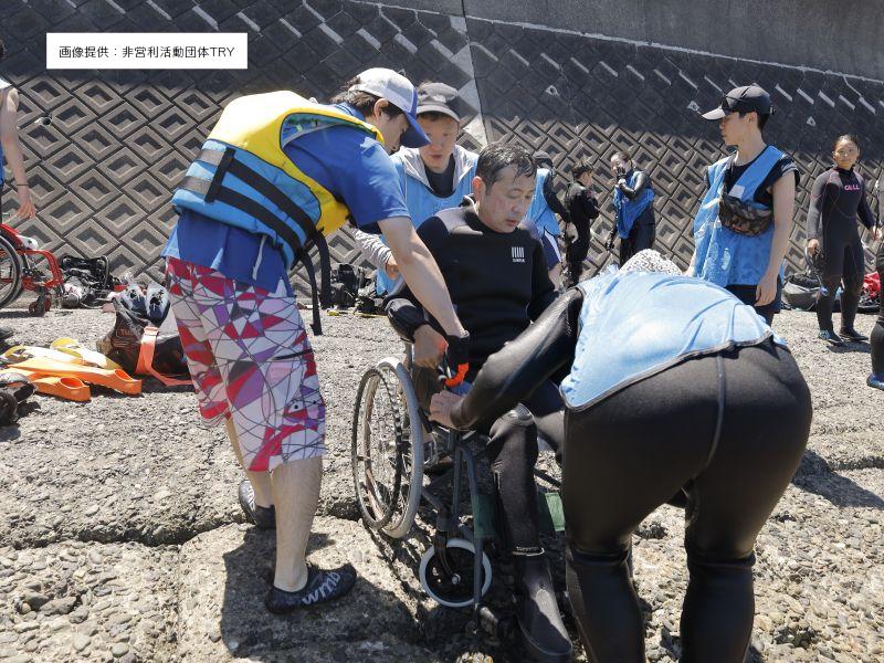 海に入る車イスの人