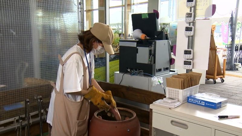 つぼにサツマイモをセットする店のスタッフ