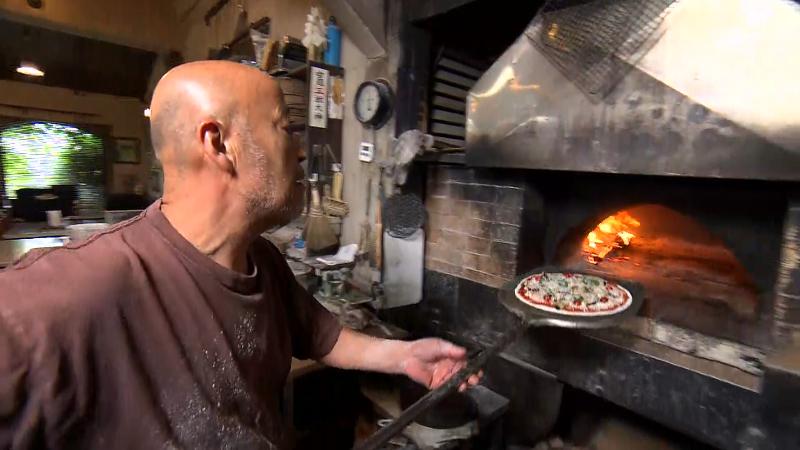 薪窯にピザを入れている