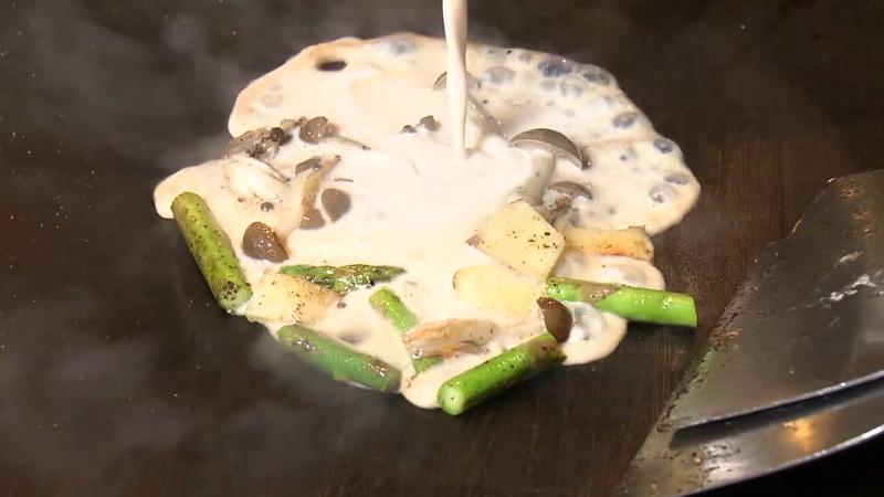 鉄板でアスパラなどの具材を炒める調理風景