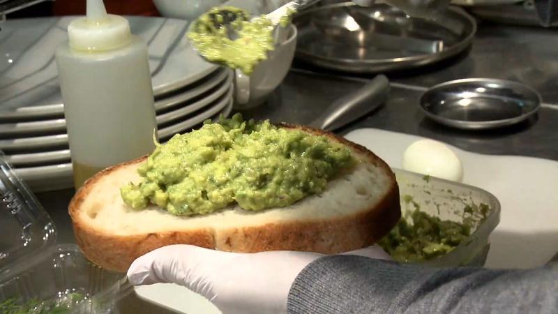 パンにアボカドをのせる調理風景